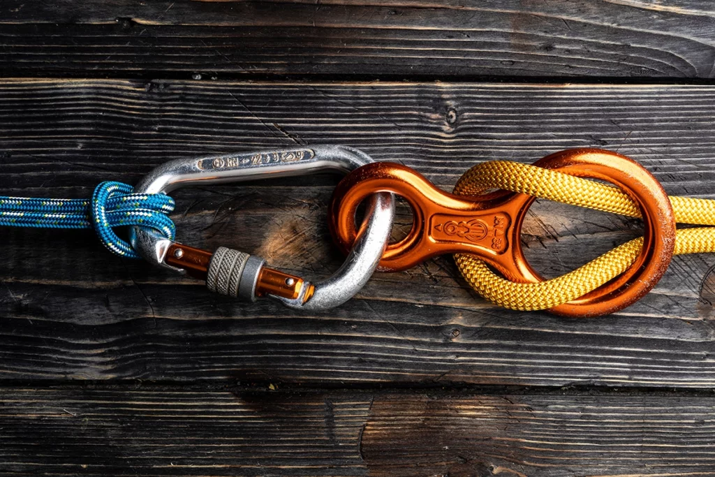Ein Sicherungsseil und Karabiner auf einem Holztisch