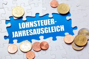 Schriftzug Lohnsteuerjahresausgleich von weißer Puzzleoptik und Hartgeld umgeben