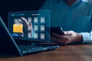 Person verwaltet digitale Dokumente auf Laptop und Smartphone mit virtueller Ordneransicht.