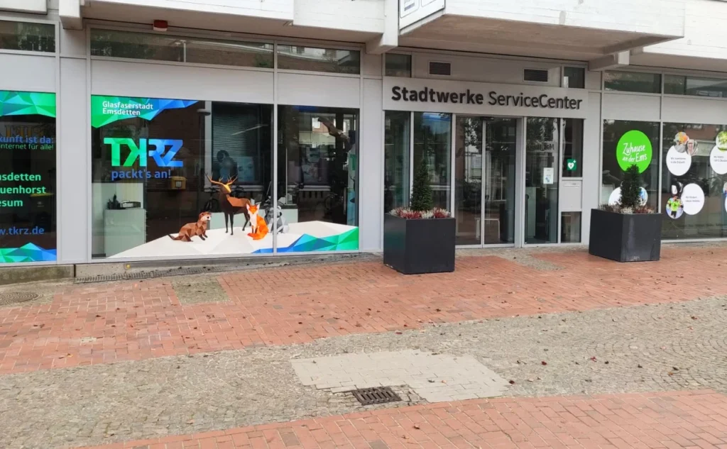 Schaufenster des Stadtwerke ServiceCenters Emsdetten mit TKRZ-Glasfaserwerbung und modernem Schaufensterdesign
