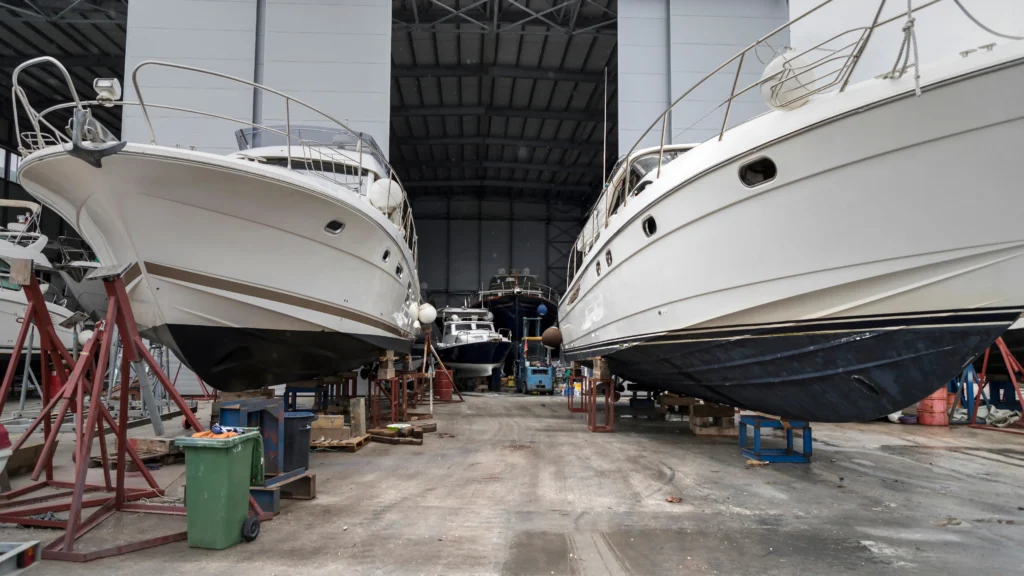 Zwei Motoryachten stehen aufgebockt in einer großen Werfthalle zur Wartung und Instandhaltung